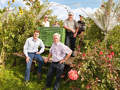 © Feneberg/Bio mit Gesicht Betriebsleiter und Sohn vor Erntewagen mit Team