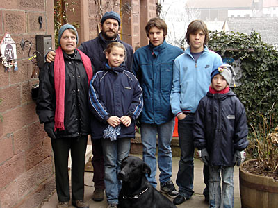 Familie mit Hund vor der Haustür im Winter