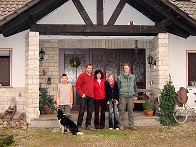 Betriebsleiterfamilie mit Hund vor Wohnhaus