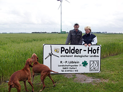 © Bio mit Gesicht Betriebsleiterehepaar mit Hunden bei Hofschild
