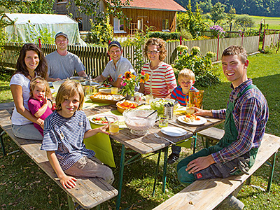© Feneberg/Bio mit Gesicht Betriebsleiter mit Familien am Gartentisch