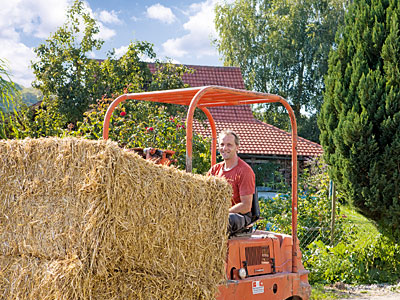 © Feneberg/Bio mit Gesicht Betriebsleiter auf Gabelstapler mit Strohballen