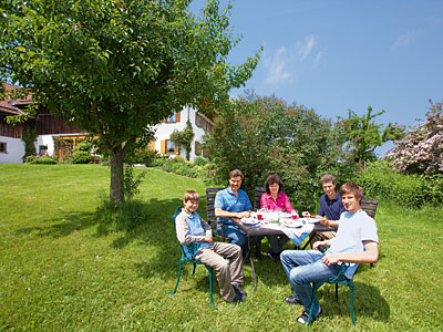 © Feneberg/Bio mit Gesicht Familie am Tisch im Garten sitzend