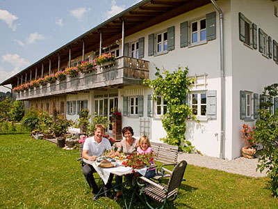 © Feneberg/Bio mit Gesicht Familie am Tisch vor dem Wohnhaus