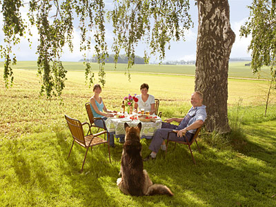 © Feneberg/Bio mit Gesicht Familie am Tisch unter einem großen Baum