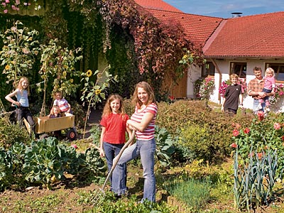 Familie im Garten vor Wohnhaus