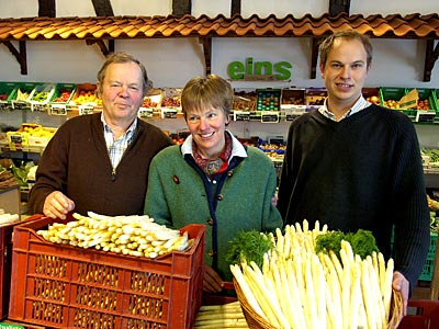 Eltern und Sohn im Hofladen mit Spargel