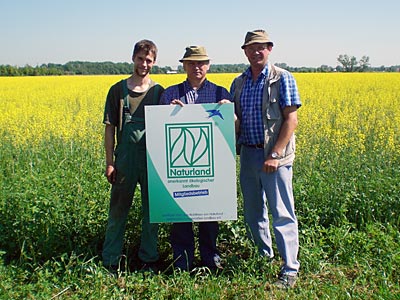 © Bio mit Gesicht Drei Männer mit Naturland Schild